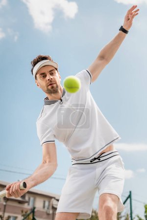 balle de tennis floue au premier plan, beau joueur de tennis jouant sur le court, la motivation et le sport