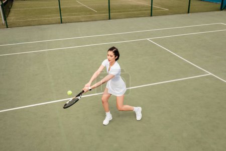 Photo for Forehand, overhead view of female player in active wear playing tennis, racket and ball, sport - Royalty Free Image
