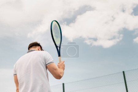 widok z tyłu sportowiec trzyma rakietę tenisową na korcie przed niebem, motywacja, sport