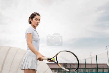 Téléchargez les photos : Sportive tenant une raquette de tennis sur le terrain, tenue active, sportive et sportive, motivation, santé - en image libre de droit