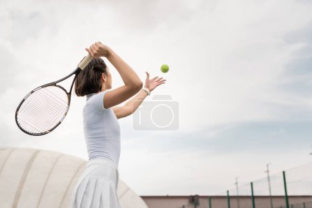 back view of female player hitting the ball while playing tennis on court, motivation and sport