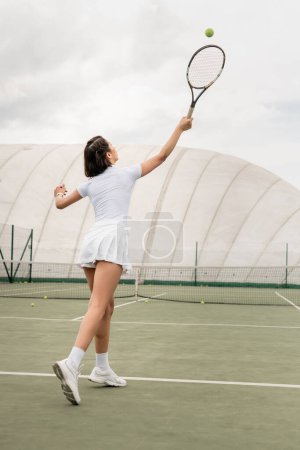 motywacja i sport, widok z tyłu sportowca uderzającego piłkę podczas gry w tenisa na korcie