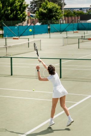 Sportlerin schlägt Tennisball auf dem Platz, hält Schläger in der Hand und spielt aktiv sportliches Spiel, Motivation