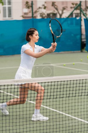 Photo for Female player playing tennis, woman in active wear holding racket on court, athletic and sporty - Royalty Free Image