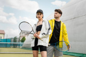 fashionable sportswear, man and woman holding tennis rackets on court, sport and style Sweatshirt #665314952