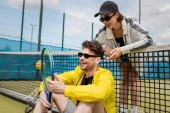 happy man and woman in active wear resting near tennis net on court, sportswear fashion, sport puzzle #665315490