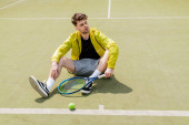 handsome man in active wear resting on tennis court, male tennis player with racket, sport hoodie #665316256