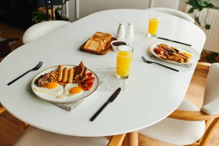Tasty breakfast with fried eggs near toasts and orange juice on table at home in morning