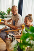 Smiling couple with orange juice having breakfast near border collie dog at home in morning Longsleeve T-shirt #665725684
