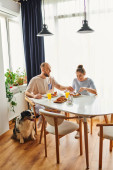 Smiling couple in homewear having breakfast together near border collie dog at home in morning t-shirt #665725788