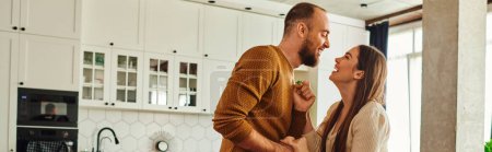 Téléchargez les photos : Vue latérale du couple positif tenant la main tout en dansant dans le salon à la maison, bannière - en image libre de droit