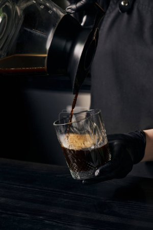 alternative Brauweise, Barista gießt frischen und köstlichen Espresso aus Kaffeekanne ins Glas