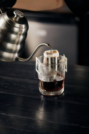 brebaje alternativo, agua hirviendo vertiendo en vidrio con café en bolsa de filtro, espresso vertido