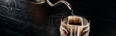 boiling water pouring from metallic kettle into glass with ground coffee in paper filter bag, banner