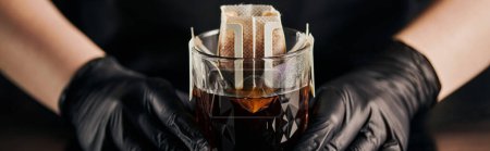 Photo for Barista in black gloves preparing coffee in crystal glass and paper filter bag, drip method, banner - Royalty Free Image