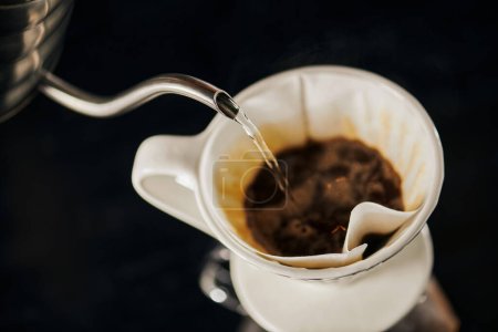 V-60 w stylu espresso, wrząca woda wlewająca się do ceramicznego kroplownika z czarną mieloną kawą