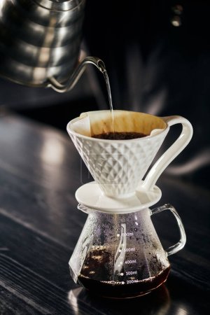 Photo for Alternative V-60 style espresso brew, boiling water pouring into ceramic dripper placed on glass pot - Royalty Free Image