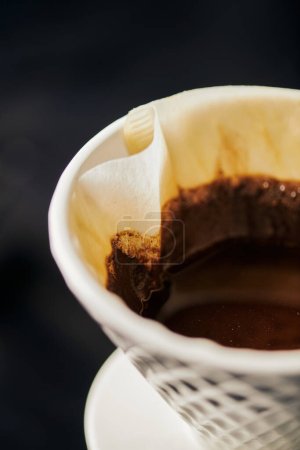 Nahaufnahme des keramischen Tropfers mit Papierfilter und schwarzem Kaffee, Espressomaschine im V-60 Stil