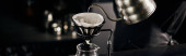 barista pouring boiling water into coffee filter on dripper stand above glass pot, V-60 style, banner magic mug #666431920