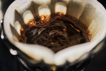 close up view of black freshly brewed coffee with foam in filter bag, alternative V-60 espresso brew