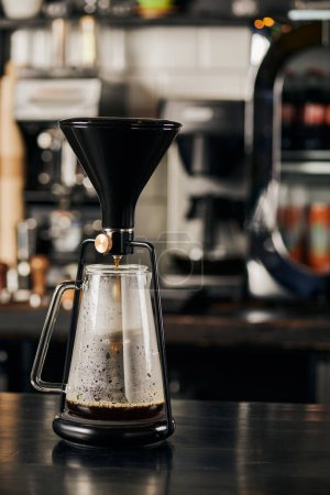 ekspres do kawy syfon ze świeżym espresso w szklanym dzbanku na czarnym drewnianym stole w nowoczesnej kawiarni