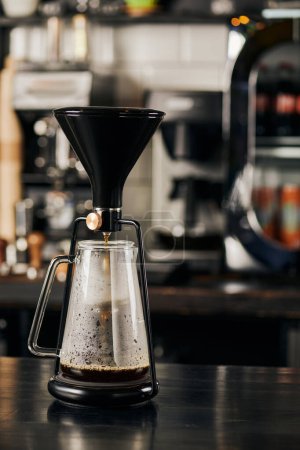 Photo for Siphon coffee maker with fresh espresso in glass coffee pot on black wooden table in modern cafe - Royalty Free Image