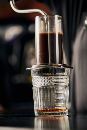 Photo for Boiling water pouring into aero press coffee maker above crystal glass, espresso brewing method - Royalty Free Image