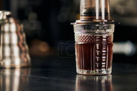 Photo for Crystal glass with aromatic and freshly brewed espresso prepared in aero press coffee maker - Royalty Free Image