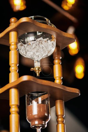 low angle view of cold drip coffee maker with ice cubes and ground coffee, alternative espresso brew