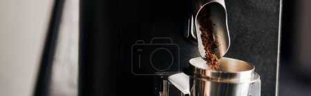 metaliczny kubek pomiarowy w pobliżu mielonej kawy i elektrycznej młynka do kawy, sprzęt baristyczny, baner