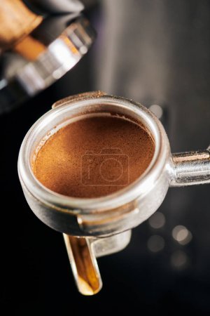 aromatic ground coffee in portafilter near tamper, espresso preparation, coffee shop