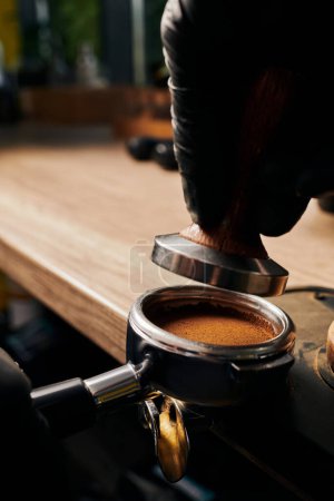 barista holding tamper above portafilter with grinded coffee, espresso, manual press, arabica 