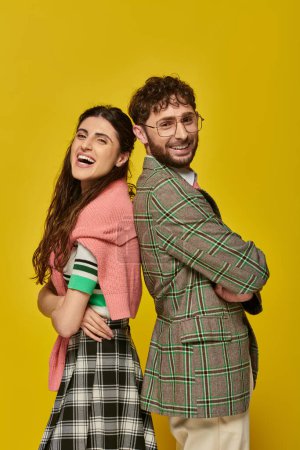 Téléchargez les photos : Heureux élégant homme et femme debout dos à dos, posant, fond jaune, tenue étudiante, rire - en image libre de droit