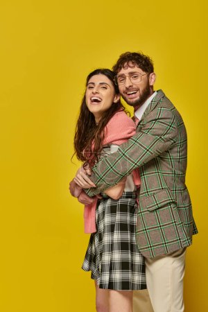 happy man hugging young woman laughing, posing, yellow background, student outfit, positivity, style
