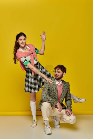 couple drôle, jeune homme et femme heureux geste, posant sur fond jaune, tenue étudiante