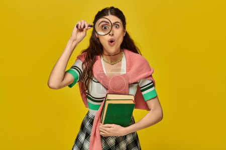 curious young woman holding books and magnifier, zoom, discovery, student in college outfit, yellow