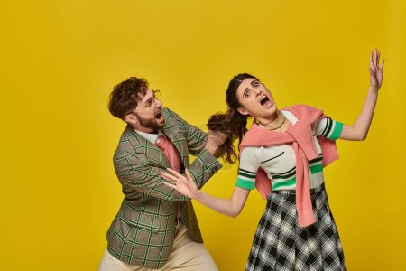 bearded man pulling hair of scared woman on yellow background, conflict, physical, young couple