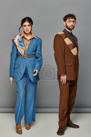 pareja elegante, sesión de moda, hombre y mujer en trajes posando sobre fondo gris, marrón, azul, tendencias