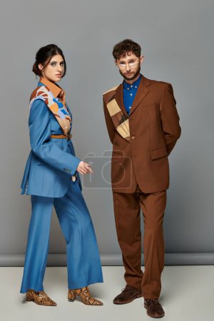 trendy couple, fashion shoot, man and woman in suits posing on grey backdrop, brown, blue, style