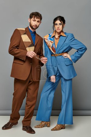 Paar und Mode, Models posieren in formeller Kleidung, blicken in die Kamera, grauer Hintergrund, elegante Anzüge
