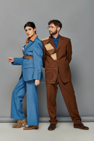 Models in maßgeschneiderten Anzügen posieren auf grauem Hintergrund, Mann und Frau in formeller Kleidung, elegant