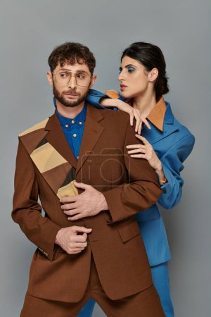stilvolle Männer und Frauen in Anzügen posieren auf grauem Hintergrund, eleganter Stil, formale Kleidung, anspruchsvolle