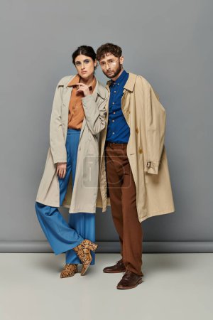 Trendpaar in Trenchcoats, Modeschuss, Mann und Frau, Oberbekleidung, grauer Hintergrund, Stil