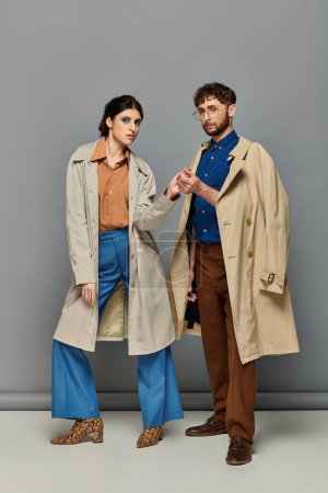 Foto de Romance, pareja en abrigos de trinchera, tiro de moda, hombre y mujer, ropa de abrigo, fondo gris, estilo - Imagen libre de derechos