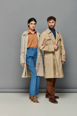 Stilvolles Paar in Trenchcoats, Modenschau, Mann und Frau, Oberbekleidung, grauer Hintergrund, Trends