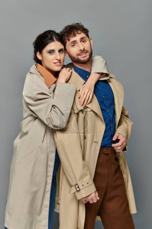 fall season, smile, man and woman hugging on grey background, couple in trench coats, style, romance
