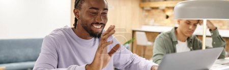 Foto de Coworking, hombre afroamericano feliz teniendo videollamada, usando el ordenador portátil, puesta en marcha, hola, gen z, bandera - Imagen libre de derechos