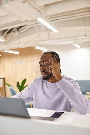 Téléchargez les photos : Homme afro-américain concentré utilisant un ordinateur portable, travaillant sur le projet de démarrage, idées, créativité, remue-méninges - en image libre de droit