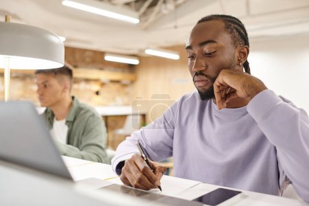 focused african american man using laptop, writing down ideas, creativity, brainstorm, startup