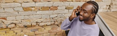 Téléchargez les photos : Jeune homme afro-américain parlant sur smartphone, souriant en coworking, startup, bannière horizontale - en image libre de droit